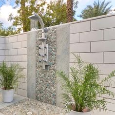 an outdoor shower with rocks and plants in pots