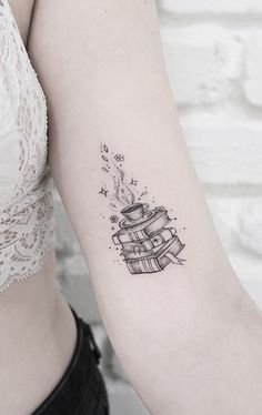 a woman's arm with a stack of books tattoo on it