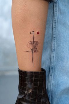 a woman's leg with a tattoo design on the side of her thigh, and a red dot in the middle