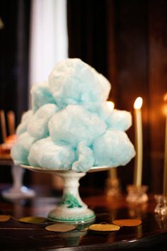 blue cotton candy on a cake plate with candles in the background