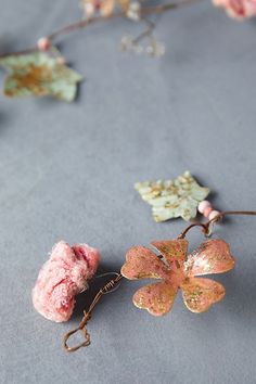 some pink flowers and leaves on a gray surface