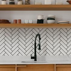 a kitchen with white and black tiles on the backsplash, wooden cabinets and open shelving