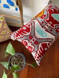 a pillow sitting on top of a wooden floor next to a potted green plant