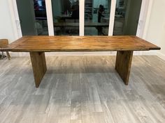 a large wooden table sitting on top of a hard wood floored floor next to a glass door