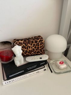 a white table topped with items like a lamp, remote control and other things on top of it