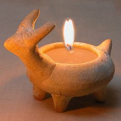 a clay animal shaped candle holder with a lit candle