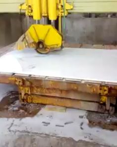 a large metal table sitting in the middle of a room next to a machine and some concrete