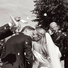 a bride and groom kiss as confetti is thrown in the air