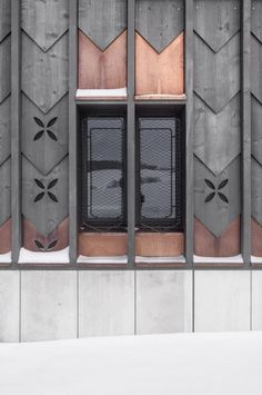 the window is decorated with geometric designs on it's sides and has snow on the ground