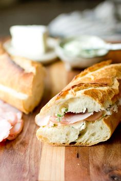 a sandwich cut in half sitting on top of a wooden cutting board next to other food items