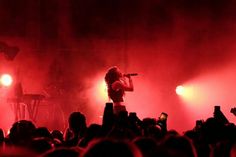 a woman standing on top of a stage holding a microphone in front of a crowd