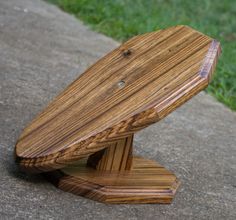 a wooden bench sitting on top of a cement ground next to green grass and trees