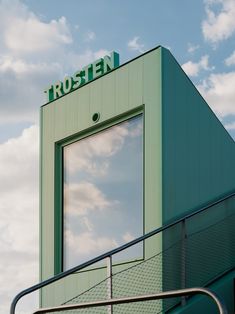 a tall green building with a sign that says frozen on it's side and the sky in the background