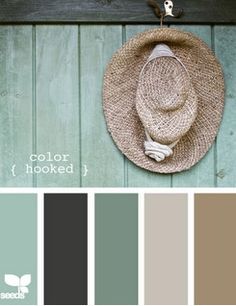 a hat hanging on the side of a wooden wall with color swatches in front of it