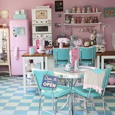 a kitchen filled with lots of white appliances and blue chairs in front of a table