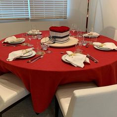 a red table topped with a cake covered in frosting and surrounded by white chairs