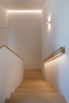 the light is shining on the wall above the stairs in this modern house with white walls and wood flooring