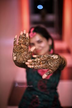 a woman holding her hands up with henna on it