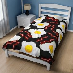 a bed with an egg and bacon pattern on it in a blue room next to a window