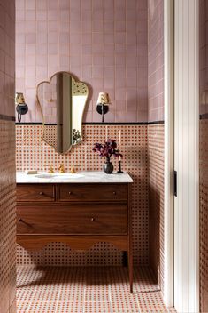 a bathroom with pink tiles and a wooden vanity