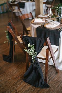 the table is set with black linens and greenery for an elegant wedding reception