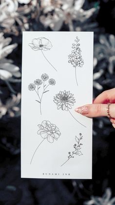 a person holding up a piece of paper with flowers on it