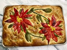 a loaf of bread decorated with flowers and leaves on a marble counter top, ready to be baked