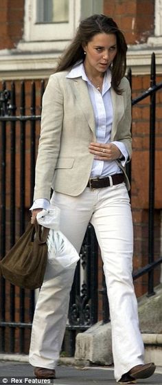 the woman is walking down the street with her hand in her pocket and wearing white pants