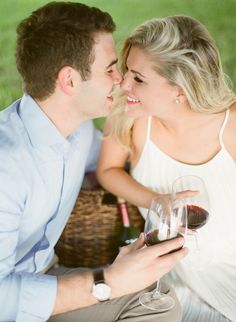 a man and woman sitting next to each other holding wine glasses