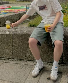 a boy sitting on a ledge with a drink in his hand