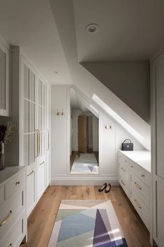 an attic bedroom with white walls and wooden flooring, built - in closets