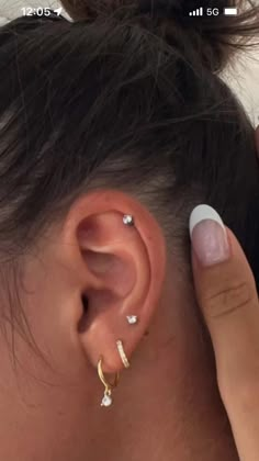 a woman with her ear piercings in the shape of three small diamond studs