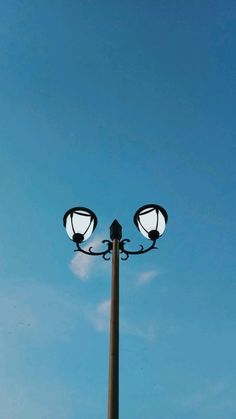 a street light with two lights on each side and a blue sky in the background