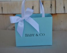 a baby and co bag with a white bow on it sitting on a table in front of a wooden wall