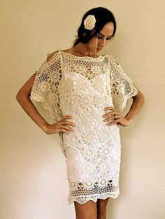 a woman standing in front of a wall wearing a white crochet dress with short sleeves