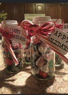 three glass jars filled with candy canes on top of a kitchen counter next to a christmas tree