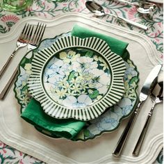 a plate with flowers on it is sitting on a place mat next to silverware