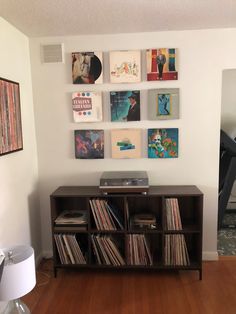 a record player sitting on top of a wooden shelf next to a wall filled with records