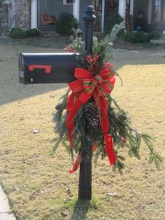 a mailbox decorated with red bows and pine cones is in front of a house