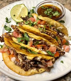 mexican food on a plate with salsa and tortilla shells, garnished with cilantro