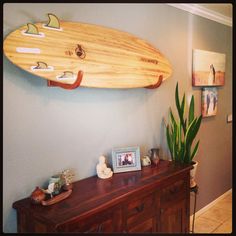 a wooden surfboard mounted to the wall above a dresser