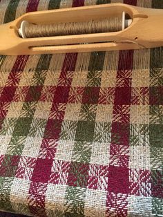 a pair of scissors sitting on top of a plaid tablecloth covered chair with red and green checkered fabric