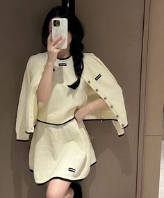 a woman taking a selfie in front of a mirror wearing a white dress and black heels