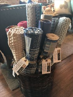 a basket filled with lots of different types of blankets on top of a wooden floor