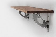 a wooden shelf with two metal gears mounted to it's sides on a white wall