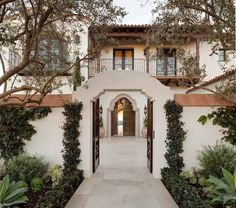 an entrance to a house with trees and bushes on either side of the entryway