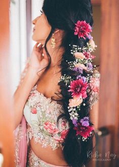 a woman with flowers in her hair is looking out the window while wearing a wedding dress