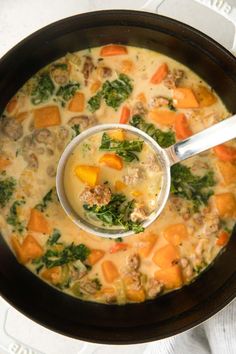 a bowl of soup with meat, carrots and spinach is shown from above