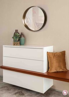 a white dresser sitting on top of a wooden bench next to a mirror and potted plant