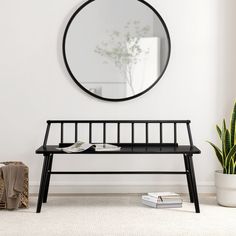 a black bench with a mirror on the wall above it and a potted plant next to it